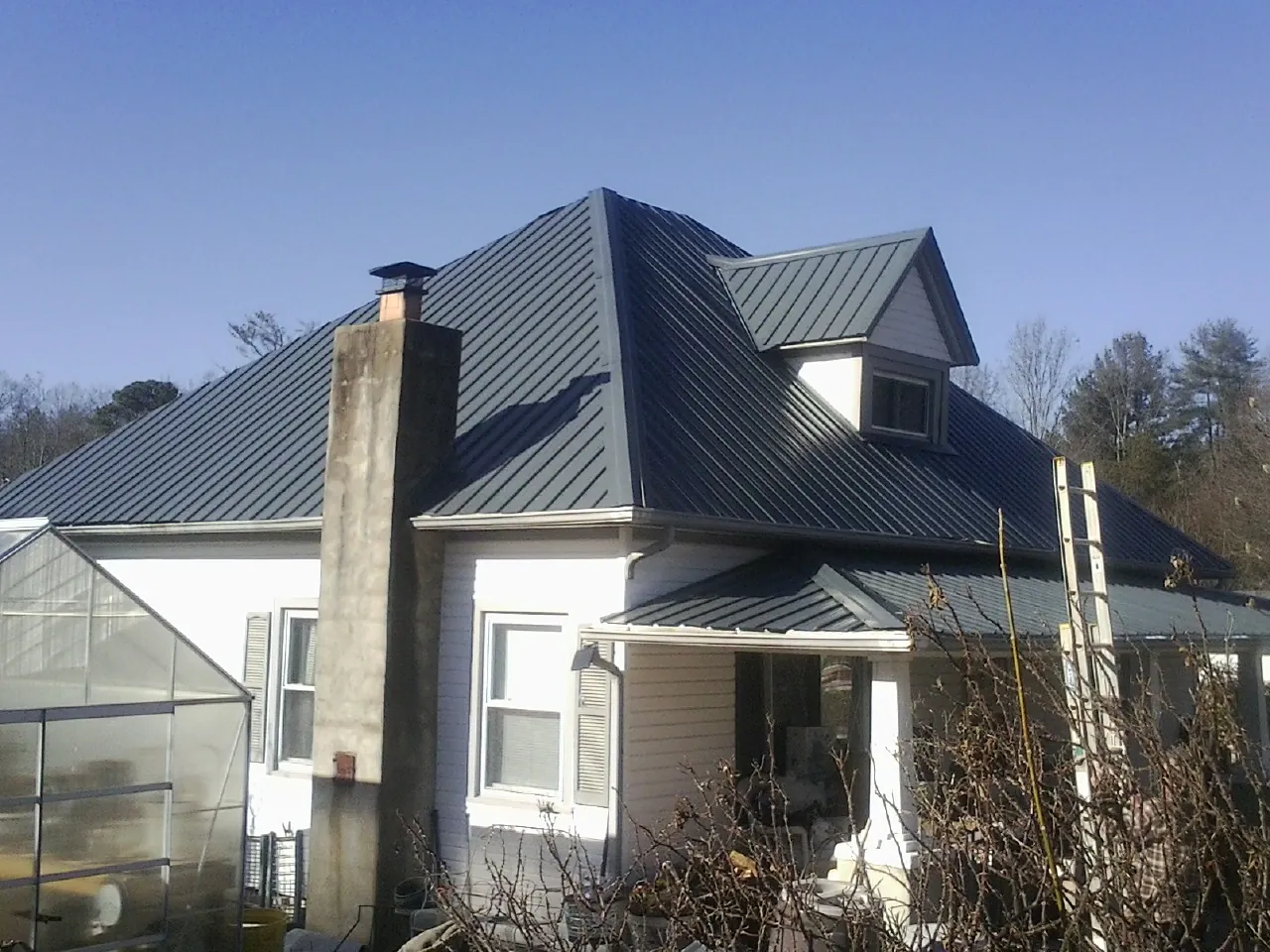 Dark blue standing seam metal roof on a white farmhouse with dormer — Slate & Tile Roof Repair by Roofing Brothers in Groveport