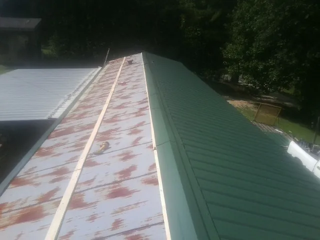 Old rusted panels beside newly installed green metal roofing — Wind Damage Roof Repair by Roofing Brothers in Groveport