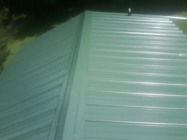 New green metal panels meeting at the ridge of a roof — Flat Roof Repair work by our crew in Groveport