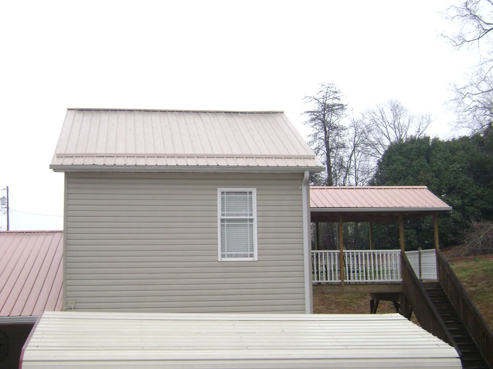 Tan metal roofs on a two story addition and attached porch, from a Roof Replacement job in Groveport