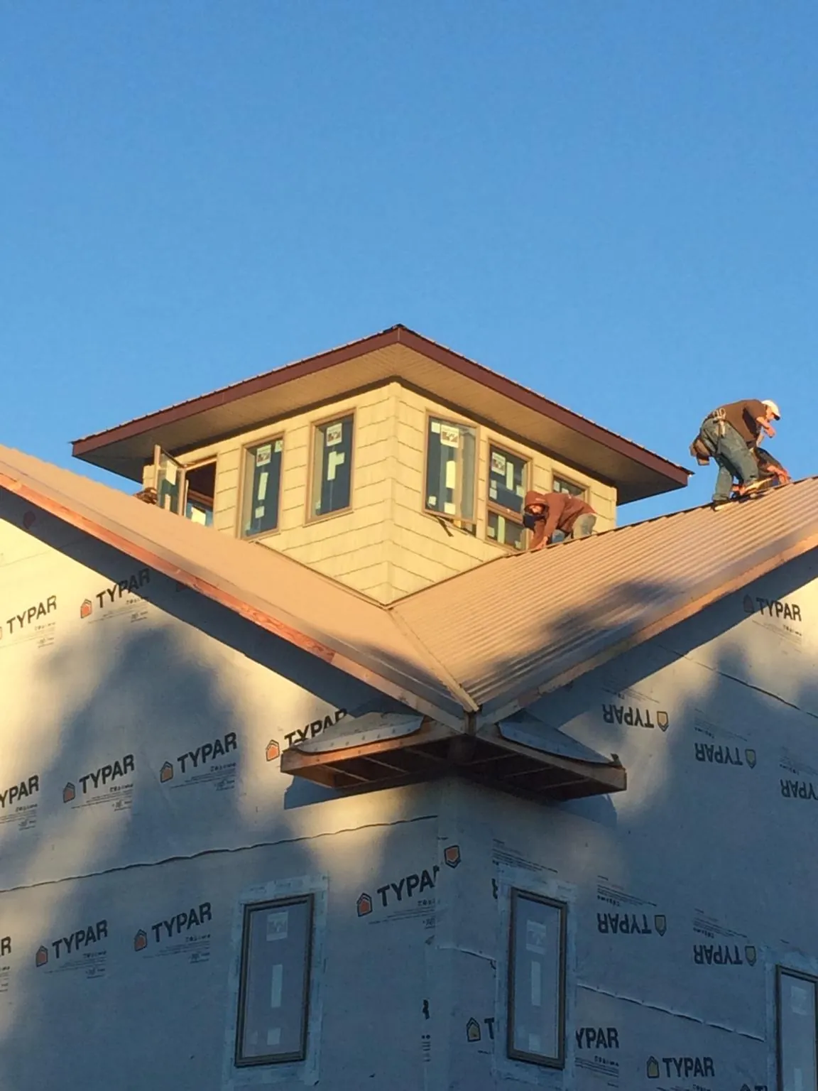 Roofers working around a rooftop cupola on a new metal roof at sunset — Roof Waterproofing in Groveport by Roofing Brothers